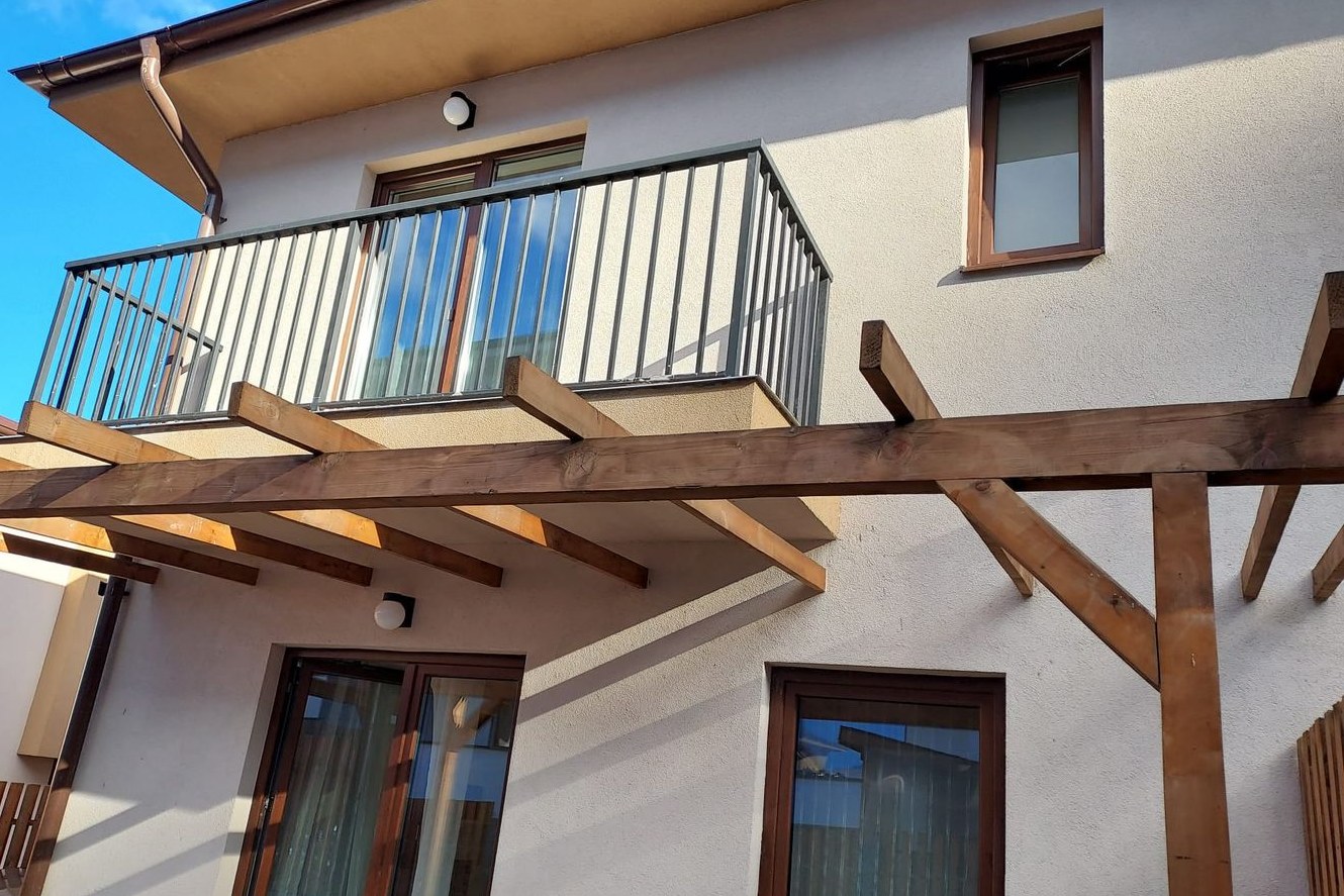 Casa de pe strada Sub Cetate din Florești, văzută din curte: terasa acoperită de pergola de lemn și balconul de la etaj